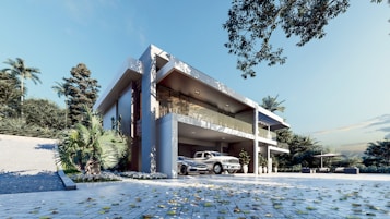 A modern two-story house with clean, angular architecture surrounded by lush greenery. The building features large glass windows and a spacious driveway with a vintage car parked in front. The setting includes a clear blue sky and scattered leaves on the ground, suggesting a breezy and serene environment.