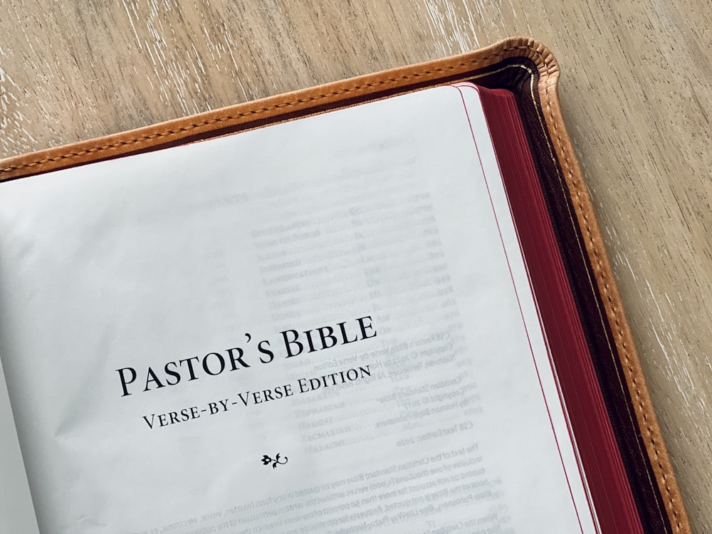 a bible opened on a table with a pen