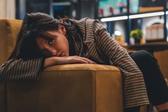 a woman sitting on a couch with her head on her hand