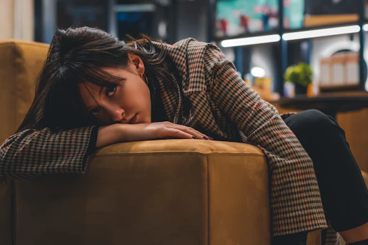 a woman sitting on a couch with her head on her hand