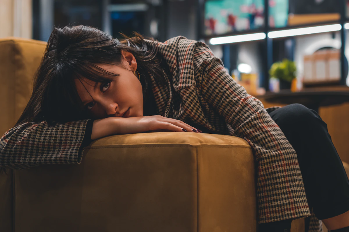 Woman looking drained and exhausted, draped over a couch — representing chronic low energy and burnout