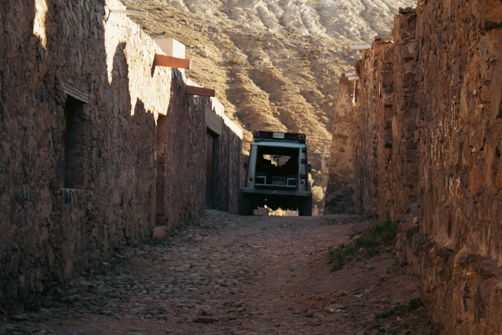 a truck driving down a dirt road next to a mountain