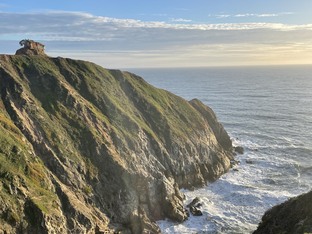 a cliff with a house on top of it next to the ocean