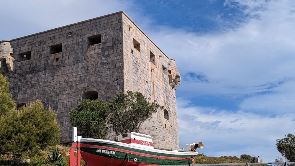 a red and white boat sitting in front of a brick building