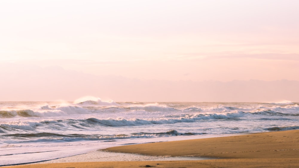 a person walking on a beach with a surfboard