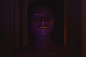 A model applying glowing highlighter with a soft brush under warm lighting