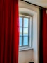 a window with a red curtain and a view of the ocean