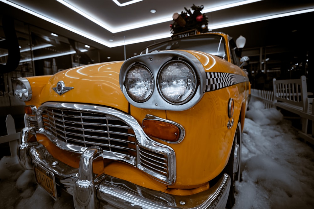 an old yellow car is parked in the snow