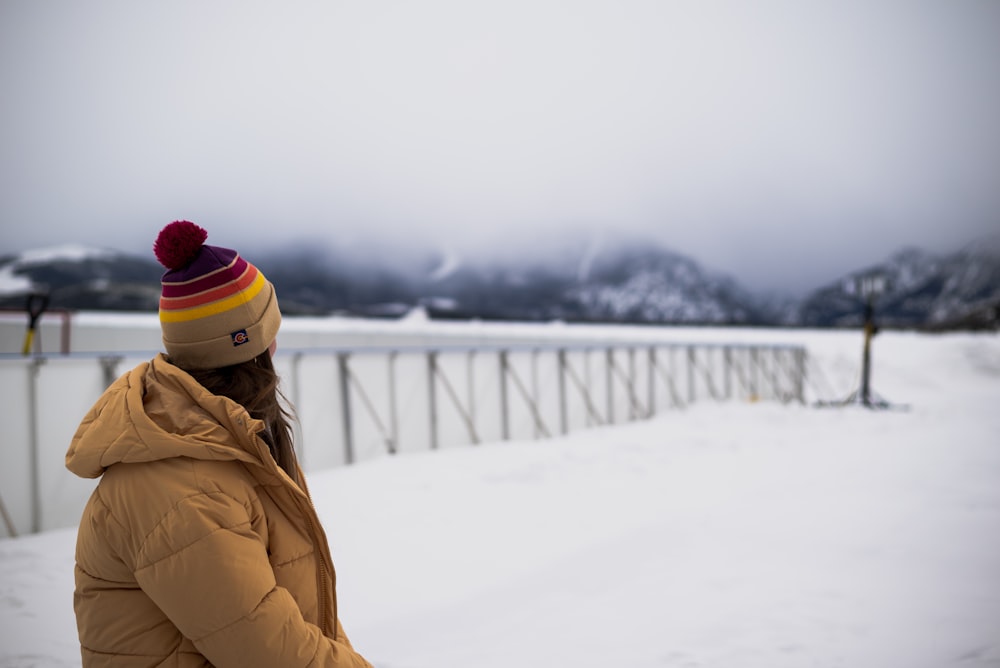 a woman standing in the snow wearing a hat