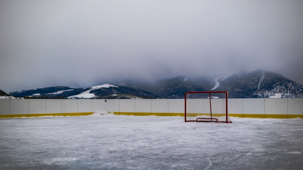 a hockey goal on an ice rink with mountains in the background