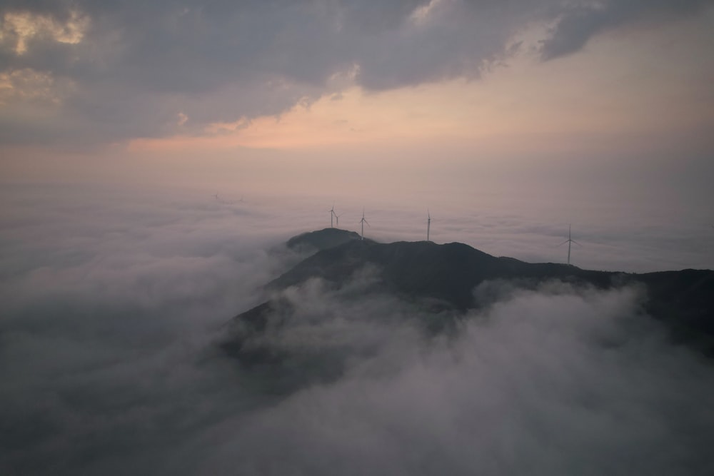 a foggy mountain with three wind mills in the distance