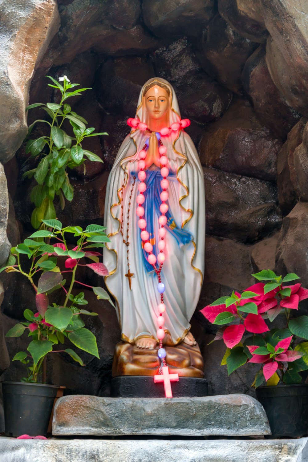 a statue of the virgin mary surrounded by flowers