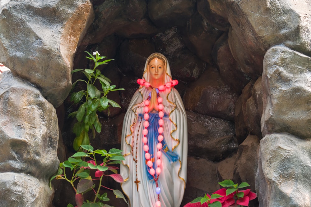 Eine Statue einer Jungfrau Maria, umgeben von Blumen