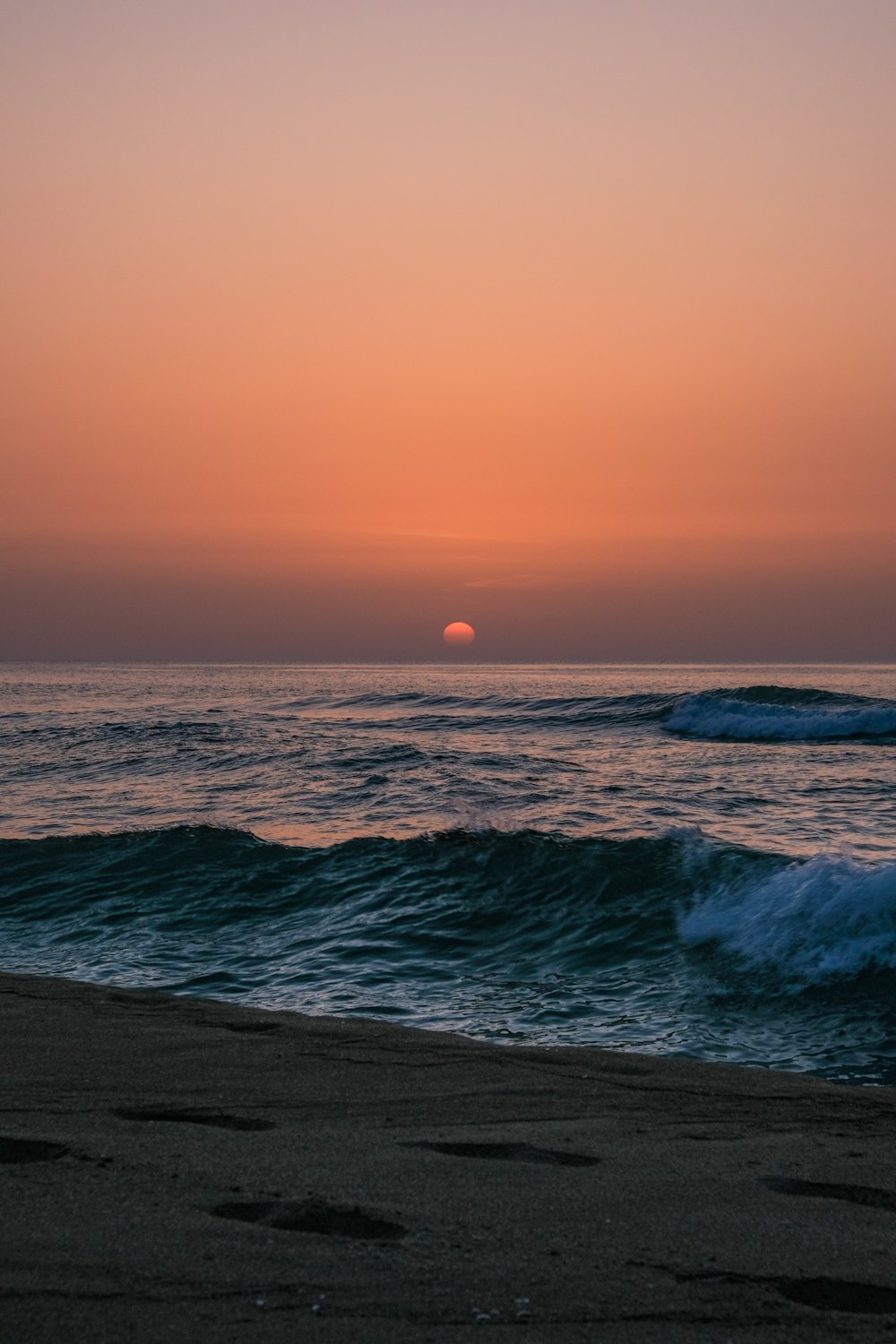 the sun is setting over the ocean with waves