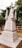 An ornately carved stone monument with a cross on top, surrounded by greenery in a cemetery setting. The monument features detailed architectural elements and a weathered appearance.