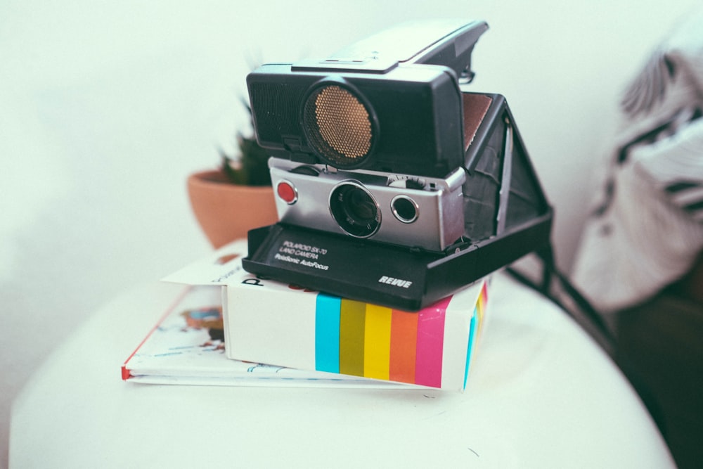 a polaroid camera sitting on top of a stack of books
