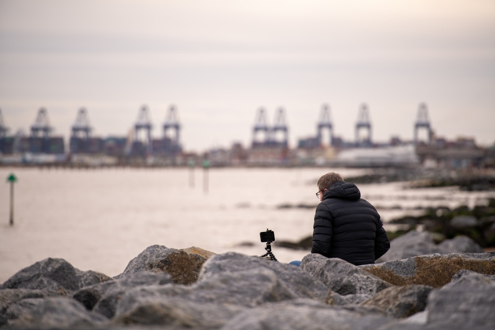 a person sitting on a rock looking at the water