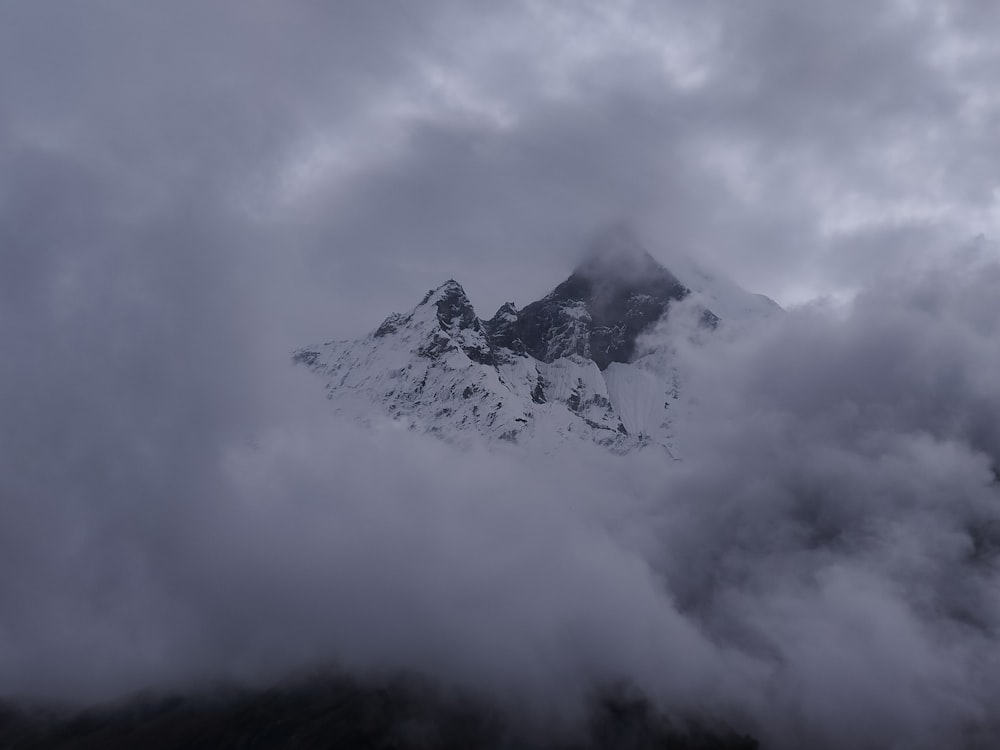 a mountain covered in clouds and snow on a cloudy day