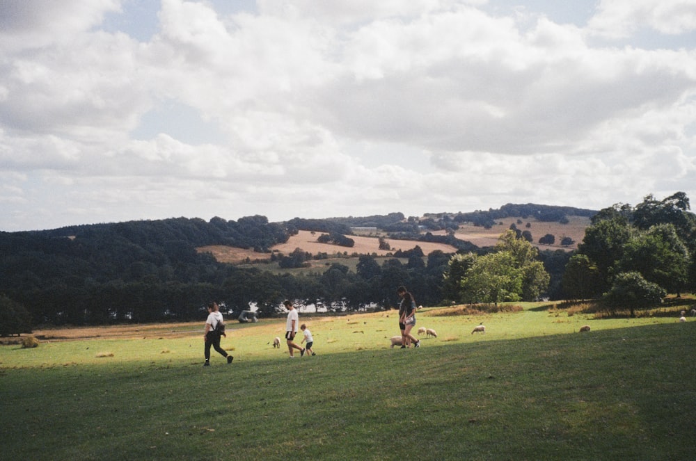 a group of people walking across a lush green field