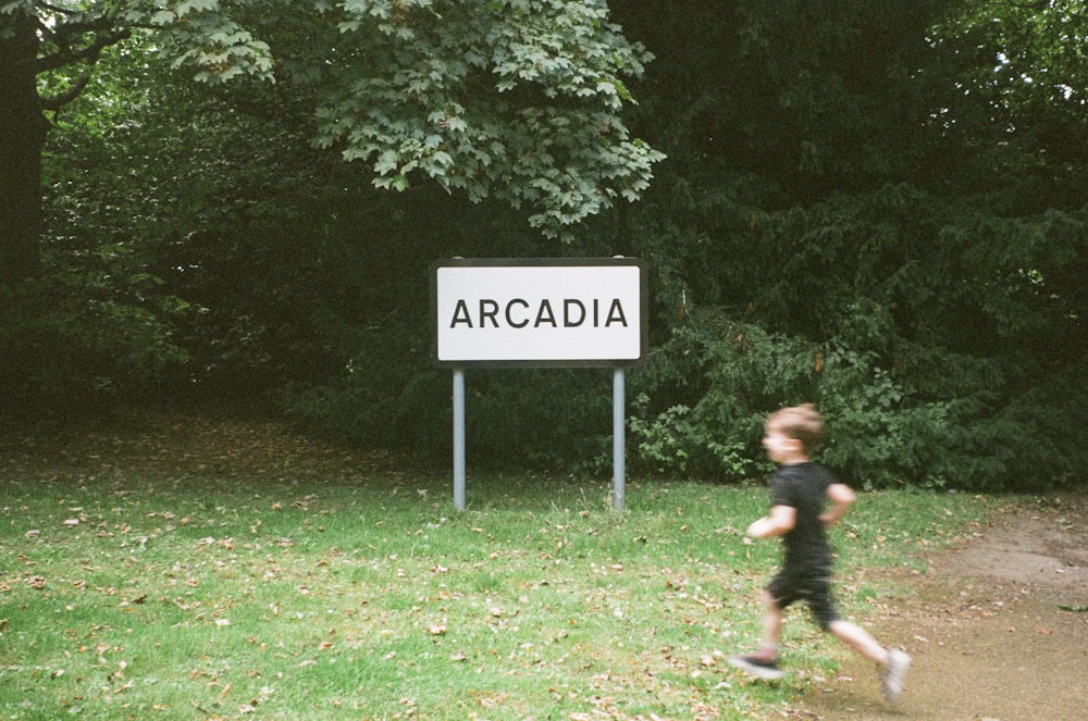 a young boy running in front of a sign