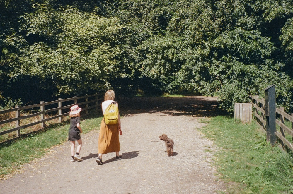 a woman and a child walking down a dirt road