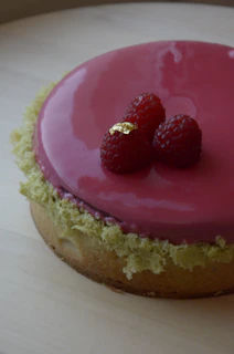 An elegant lactose-free cake topped with fresh berries and a soft pink glaze, perfect for celebrations.