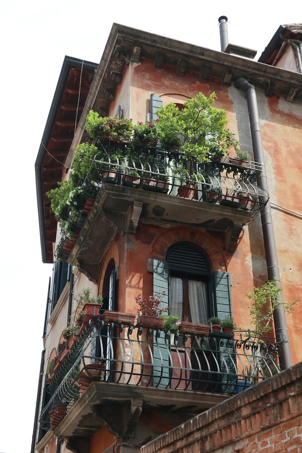 a tall building with a balcony with plants on it