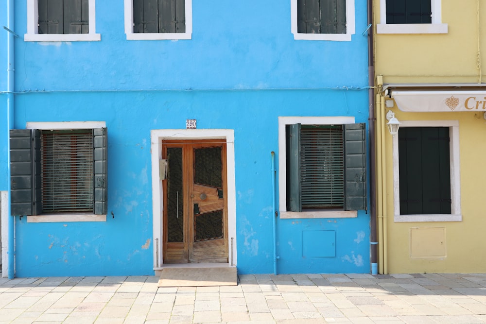 a blue building with shutters and a wooden door