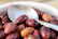 Close-up of a bowl filled with assorted fresh olives and nuts on a minimalist white table.