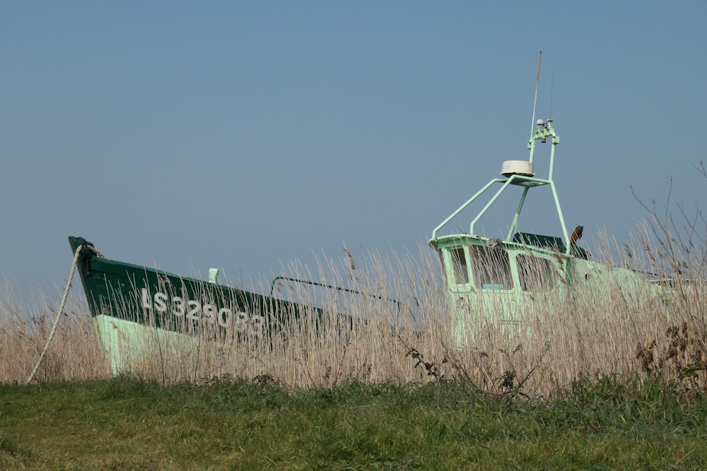 a green boat sitting on top of a lush green field