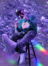 a man sitting on a stool with a cell phone in his hand