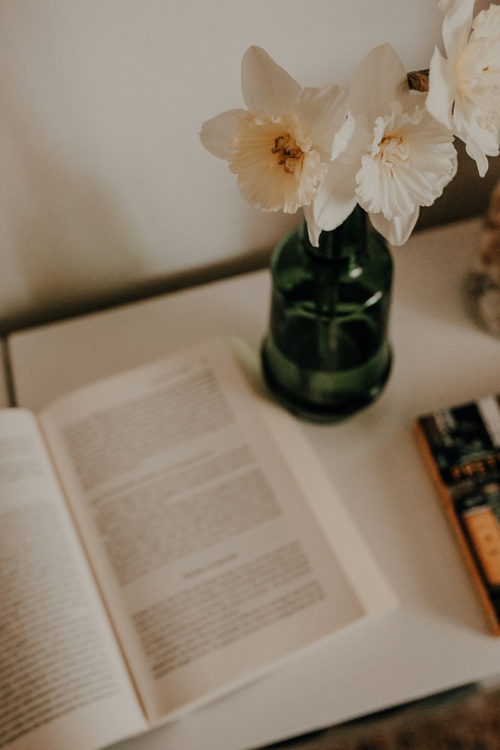 un libro y un jarrón con flores sobre una mesa