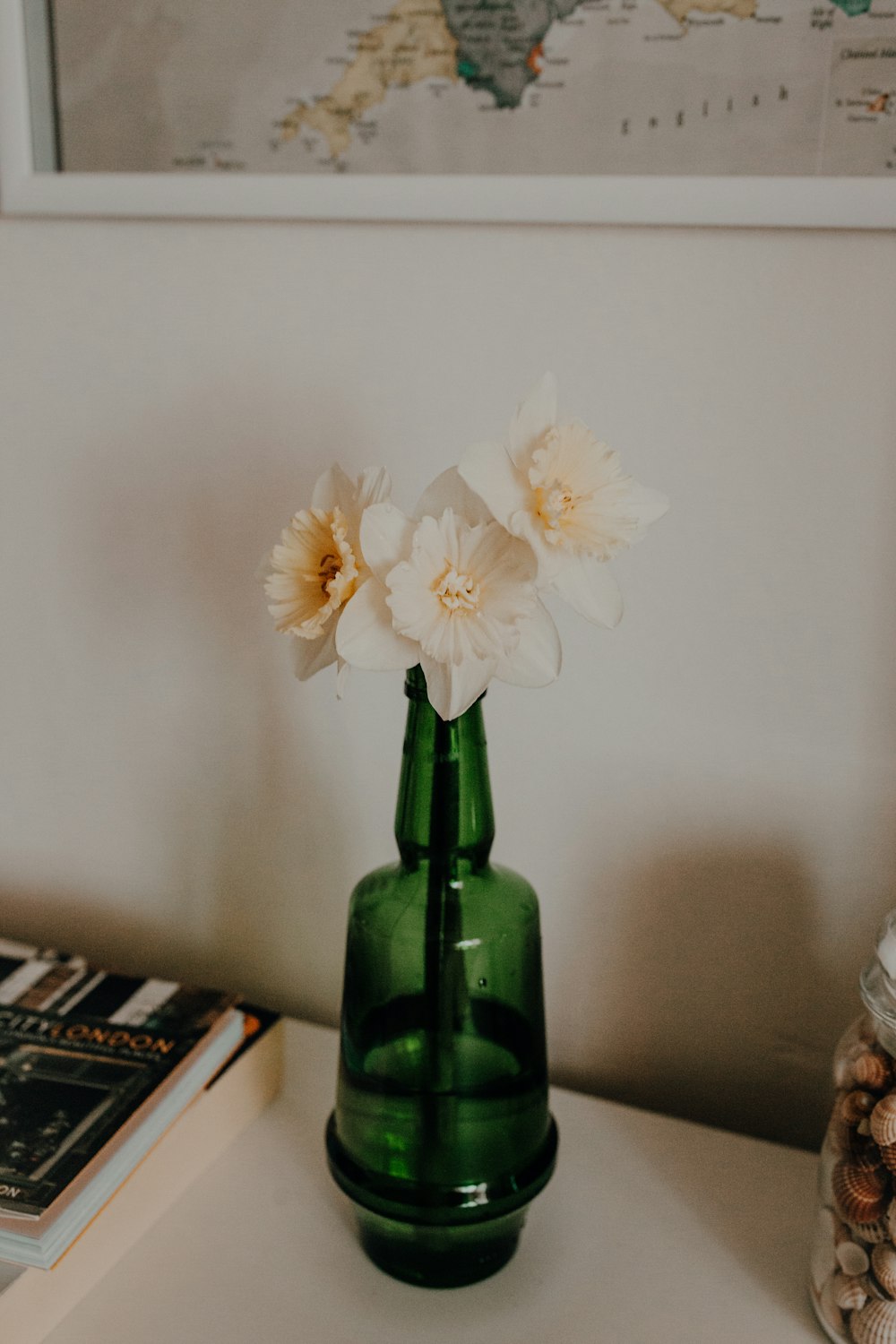 Un jarrón verde con flores blancas sobre una mesa