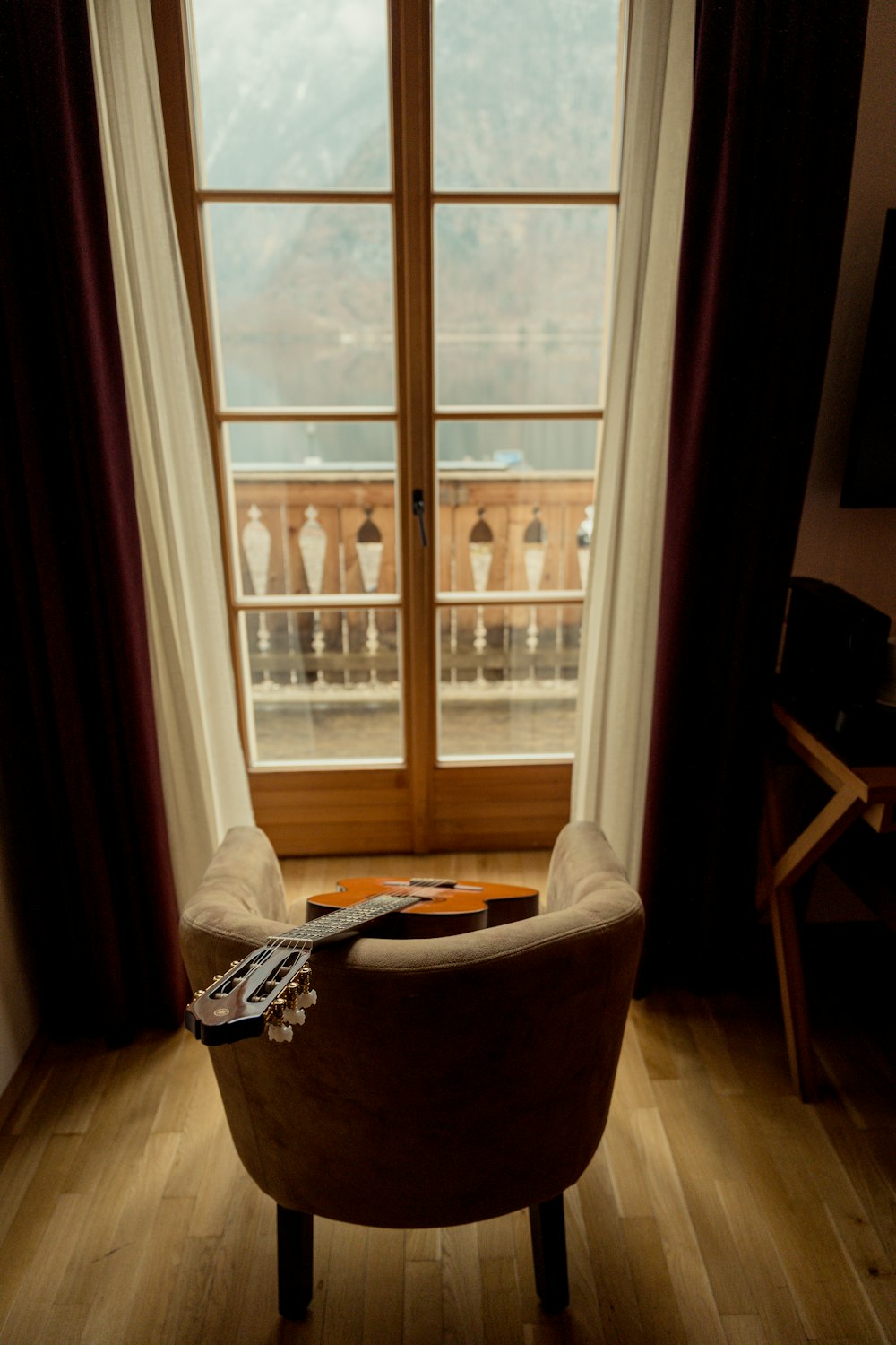 a guitar sitting on a chair in front of a window