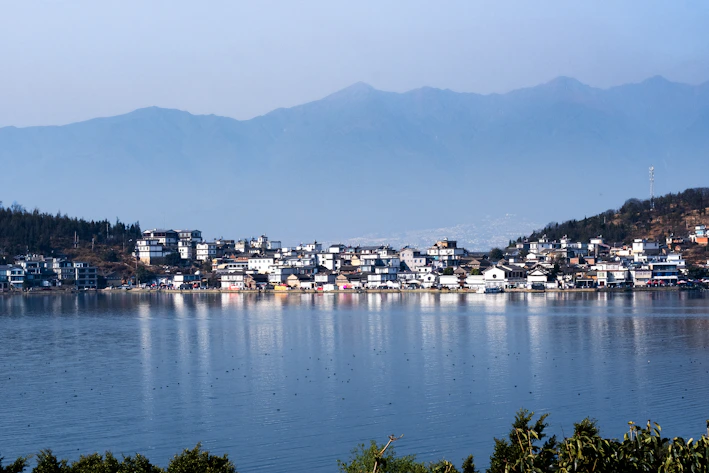 a town on a lake with mountains in the background