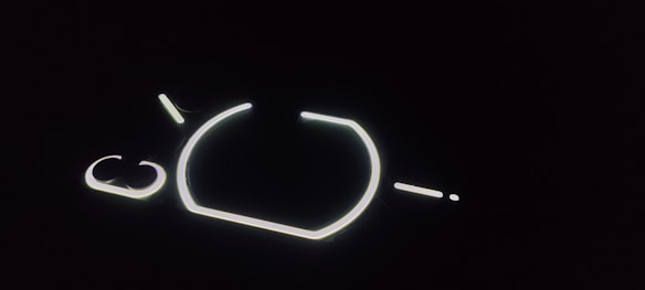 A series of illuminated lines and shapes against a dark background, forming geometric patterns possibly representing a minimalist design or abstract art.