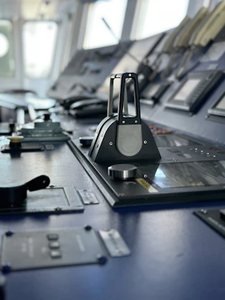 Control panel with illuminated buttons and screens inside a ship's bridge