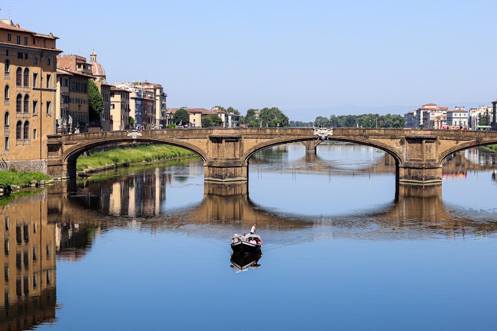 a boat floating on a river next to a bridge