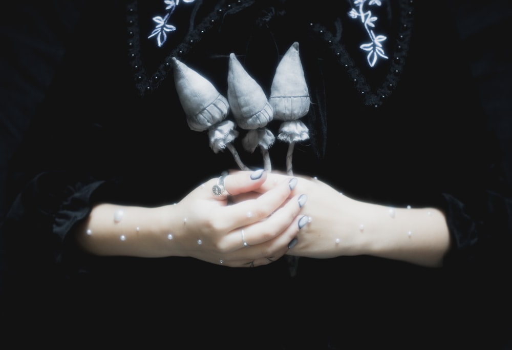 a woman's hands holding three pairs of shoes