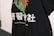 A close-up of a garment, such as a shirt or hoodie, adorned with a colorful graphic consisting of orange, green, and black colors. Below the graphic, there is text in white, which includes both large Chinese characters and smaller English text that reads 'TeenTeam Canton Local'.