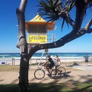 a man riding a bike down a sidewalk next to a beach