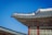 A traditional Asian building with an ornately decorated roof featuring intricate patterns and figurative sculptures. The structure is set against a clear blue sky, highlighting the detailed craftsmanship.