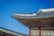 A traditional Asian building with an ornately decorated roof featuring intricate patterns and figurative sculptures. The structure is set against a clear blue sky, highlighting the detailed craftsmanship.