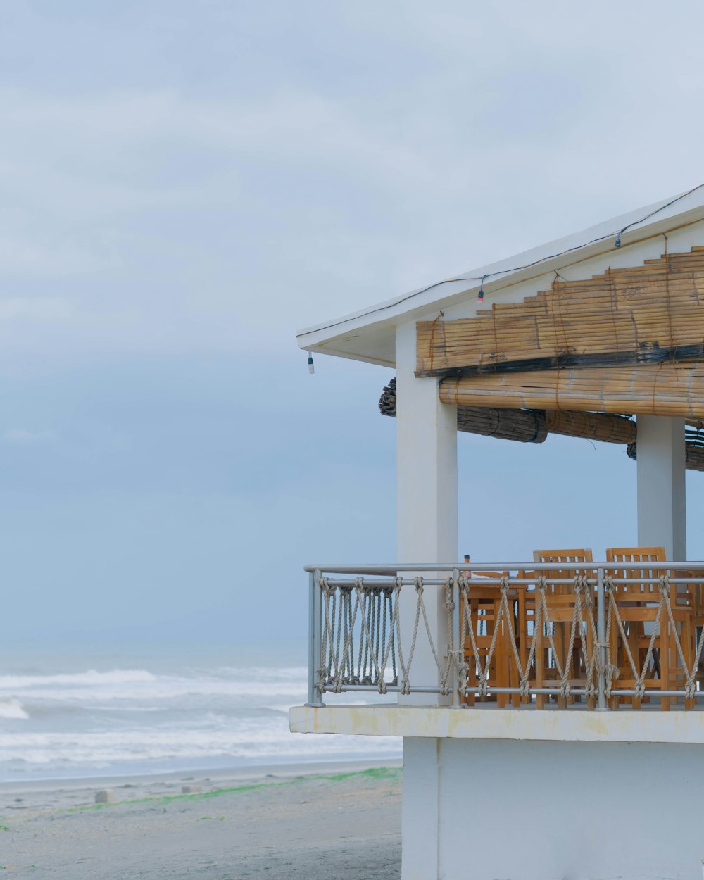 a wooden table and chairs on a balcony overlooking the ocean