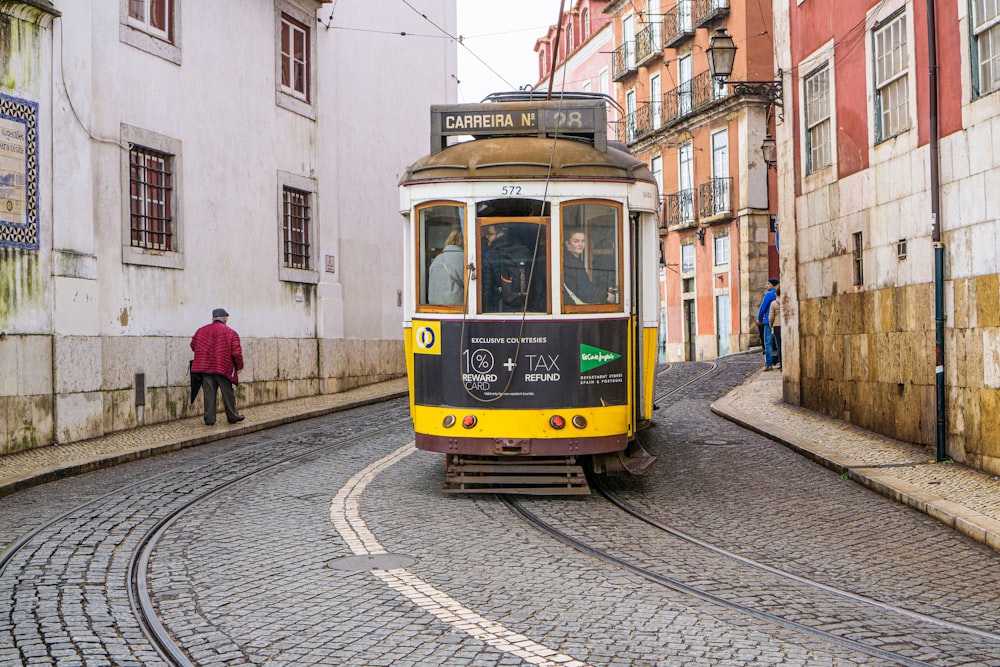 a yellow and black trolley car on a cobblestone street