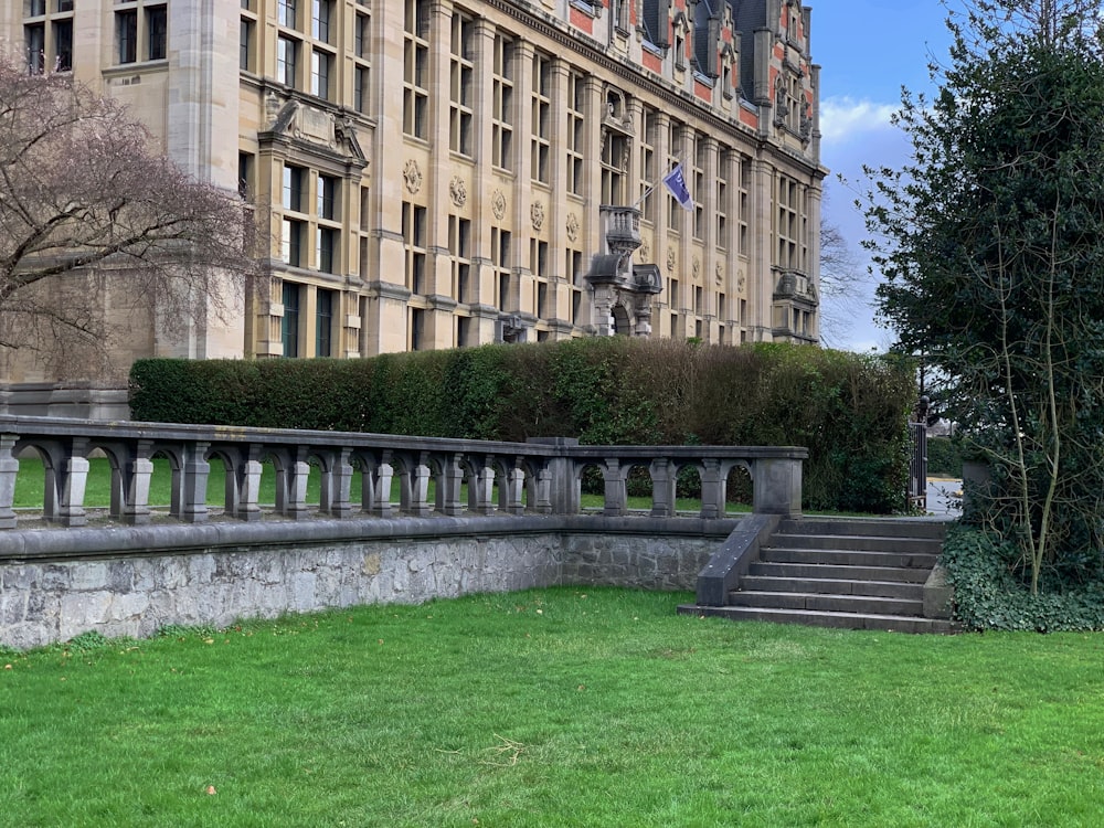 a large building with a lot of windows next to a lush green field