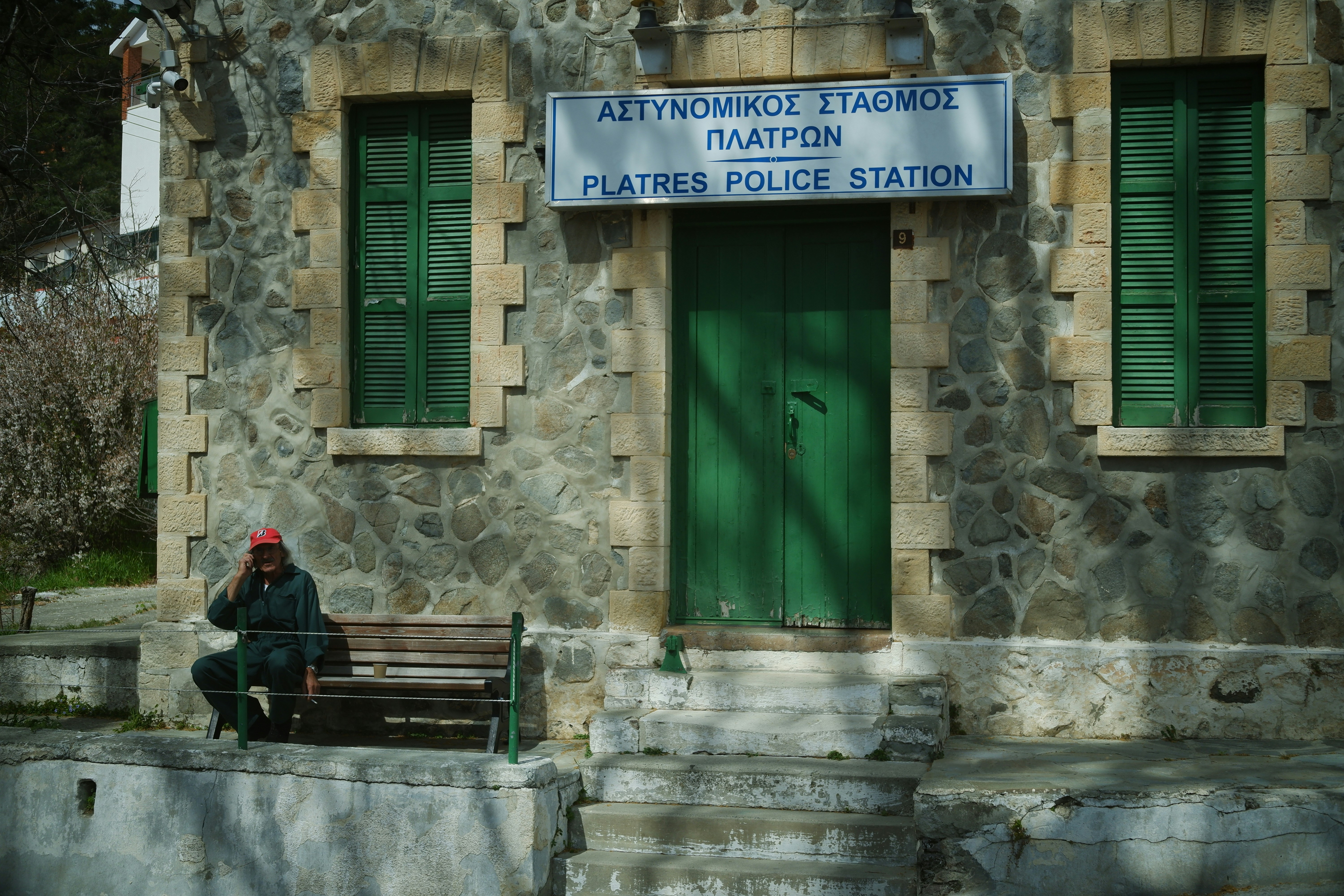 A distraught elderly couple, appearing tired and anxious, sitting on a bench outside a police station, looking helpless as if waiting for news about a missing child.