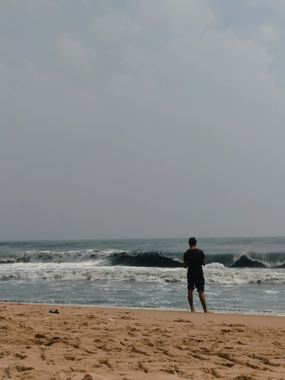 a man standing on top of a sandy beach next to the ocean