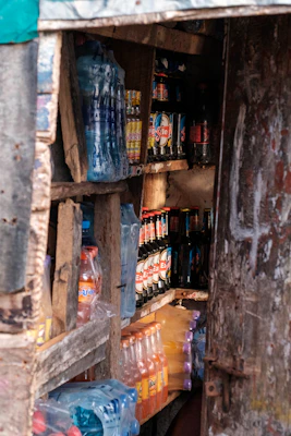 A rustic wooden shelf filled with assorted colorful bottles of beverages.