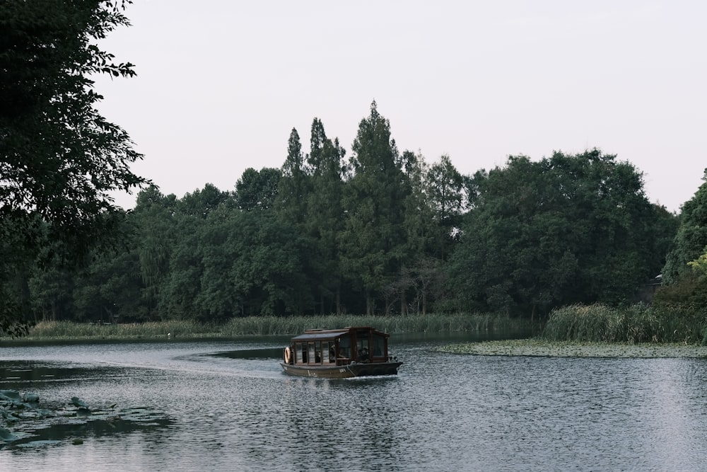 a boat traveling down a river next to a forest